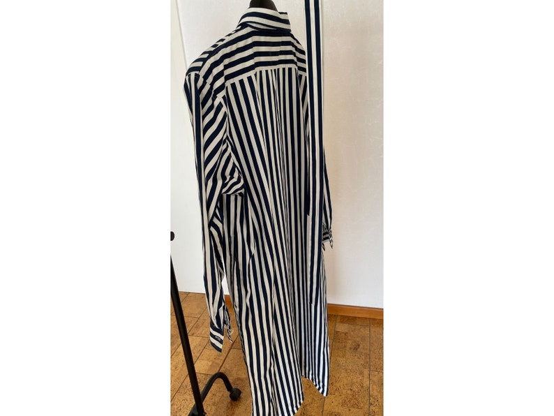 May include: A long-sleeved shirt with vertical black and white stripes. The shirt has a collar and button closure.