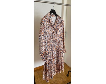 May include: A long-sleeved dress with a brown, white, and blue geometric pattern. The dress has a collared neckline and a pleated skirt.