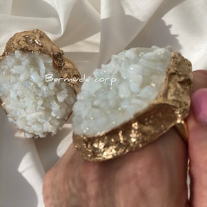 May include: Two gold rings with white crystal accents. The rings are in the shape of a rock with a rough texture.