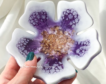 Könnte beinhalten: Eine weiße Blumenschale aus Harz mit violetten und goldenen Akzenten. Die Schale ist blumenförmig mit fünf Blütenblättern und hat eine kleine Vertiefung in der Mitte.