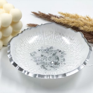May include: White resin tray with a silver rim and silver flakes embedded in the resin. The tray has a scalloped edge.