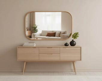 May include: A light wood sideboard with two side cabinets and two central drawers, supported by four tapered legs. Above it hangs a large, horizontally oriented rectangular mirror with rounded corners, featuring a matching light wood frame.