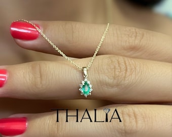 May include: A delicate gold chain necklace with a pendant featuring a pear-shaped emerald gemstone surrounded by a halo of smaller diamonds.