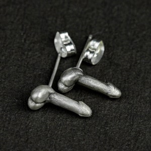 May include: A pair of silver stud earrings shaped like penises.
