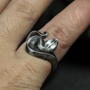 Op de afbeelding: Een zilveren slangenring met een gedetailleerd ontwerp. De slang is om de vinger gewikkeld en de kop kijkt naar voren.