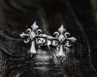 May include: Two silver cross-shaped earrings with intricate details.