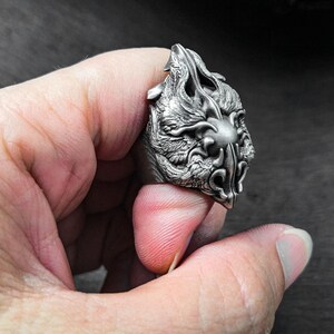 May include: A silver ring with a detailed dragon head design. The dragon's face is fierce and detailed, with sharp teeth and claws.