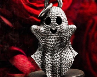 May include: A silver charm in the shape of a smiling ghost with a textured surface. The charm has a loop at the top for attaching to a necklace or bracelet.