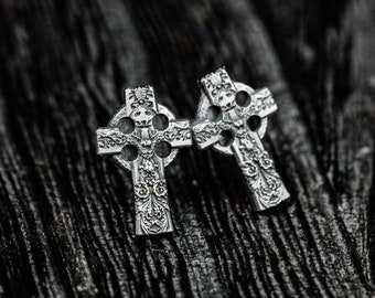 May include: Two silver Celtic cross earrings with intricate designs. The crosses are detailed with floral patterns and have a slightly aged finish.