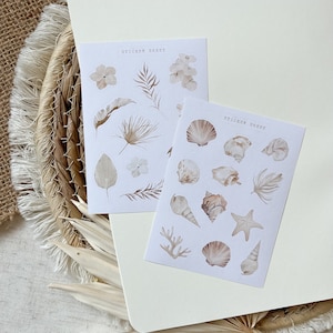 Könnte beinhalten: Zwei Stickerbögen mit Strandthema. Der erste Bogen zeigt weiße Blumen, Palmenblätter und Muscheln. Der zweite Bogen zeigt Muscheln, Palmenblätter und Seesterne. Beide Bögen haben den Text "Sticker Sheet" aufgedruckt.