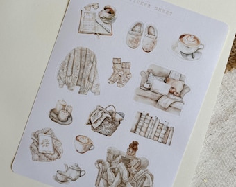 May include: A sticker sheet with illustrations of cozy winter scenes, including a person reading a book on a couch, a cup of coffee, a sweater, and a basket of books. The sheet says "Sticker Sheet" at the top.