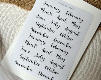 May include: A sticker sheet with the months of the year written in cursive script. The sheet includes two sets of all twelve months, January through December.