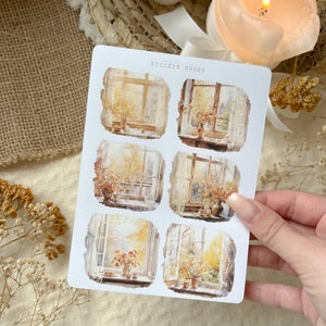 Könnte beinhalten: Ein Stickerbogen mit sechs Aquarellillustrationen von Fensterszenen mit Vasen mit Blumen. Auf dem Stickerbogen steht oben "STICKER SHEET". Die Illustrationen haben eine warme Farbpalette aus Gelb, Orange und Braun.