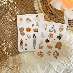 Könnte beinhalten: Zwei Stickerbögen mit Herbstthema. Der erste Bogen zeigt einen Kürbis, ein Gespenst, ein Mädchen in einem Pullover, eine Tasse Kaffee, einen Stuhl mit einem Kürbis darauf und einen Blätterhaufen. Der zweite Bogen zeigt einen Kürbis, einen Kuchen, einen Plattenspieler, einen Pullover, eine Tasse Kaffee, eine Tüte Blätter, ein Buch und eine Bank. Beide Bögen tragen oben die Aufschrift "Sticker Sheet".