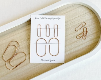 May include: Rose Gold Variety Paperclips by Glamandplan. A set of gold paperclips in different shapes and sizes, including oval and rectangular shapes.