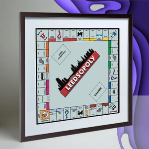 May include: A framed print of a Monopoly board game with a custom design featuring the city of Leeds. The board is light blue with red, yellow, green, and blue squares. The game title is "Leedsopoly" and is printed in red and white letters.