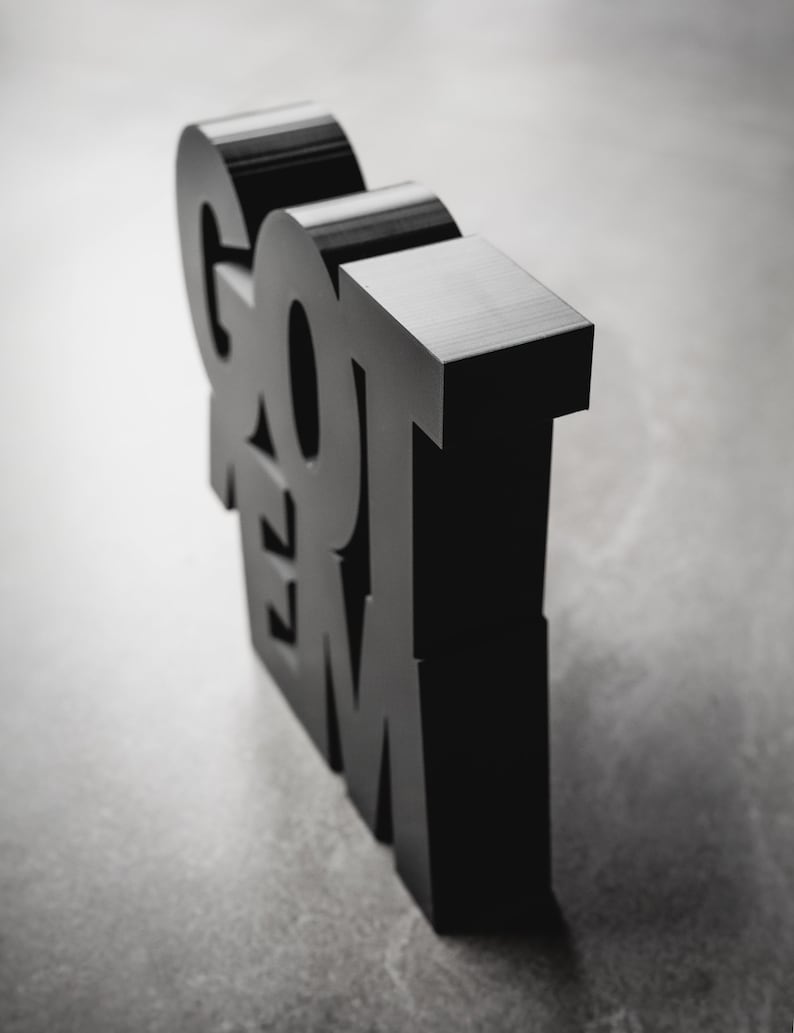 Peut inclure: Lettres 3D noires &eacute;pellant "GOT 'EM" pos&eacute;es sur une surface grise.