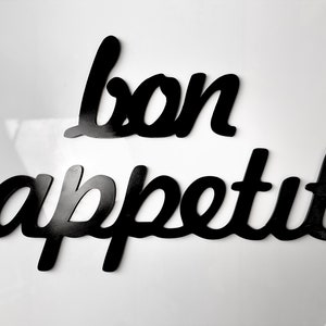 May include: Black wooden letters spelling out "bon appetit" on a white background.