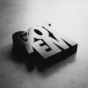 Peut inclure: Rendu 3D du mot &laquo; GOT 'EM &raquo; en noir, avec une surface l&eacute;g&egrave;rement textur&eacute;e. Les lettres sont empil&eacute;es les unes sur les autres, avec le &laquo; G &raquo; en haut et le &laquo; M &raquo; en bas.