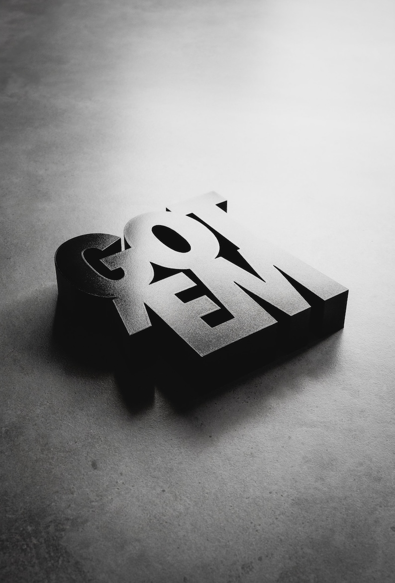 Peut inclure: Rendu 3D du mot &laquo; GOT 'EM &raquo; en noir, avec une surface l&eacute;g&egrave;rement textur&eacute;e. Les lettres sont empil&eacute;es les unes sur les autres, avec le &laquo; G &raquo; en haut et le &laquo; M &raquo; en bas.
