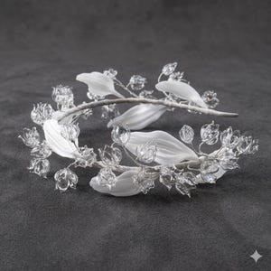 Peut inclure: Un serre-t&ecirc;te orn&eacute; d'une s&eacute;rie de fleurs en verre transparent en forme de clochettes et de feuilles blanches opaques allong&eacute;es, fix&eacute;es sur une fine armature en fil m&eacute;tallique argent&eacute;, rappelant des brins de muguet dispos&eacute;s en arc.