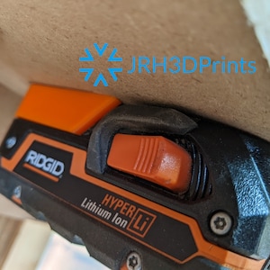 K&ouml;nnte beinhalten: Nahaufnahme eines schwarzen und orangefarbenen Elektrowerkzeugs mit dem Markennamen "RIDGID" und dem Text "HYPER Li Lithium Ion" an der Seite. Das Werkzeug hat einen orangefarbenen Ausl&ouml;ser und einen schwarzen Griff.