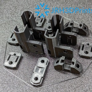 May include: A set of black 3D printed plastic parts, likely for a furniture project. The parts are arranged on a black surface with the text "JRH3DPrints" visible in the background.