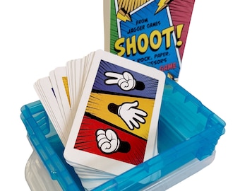 May include: A card game called "SHOOT!" based on Rock, Paper, Scissors. The game includes a deck of cards with hand gestures and a booklet. The cards are stored in a clear blue plastic container.