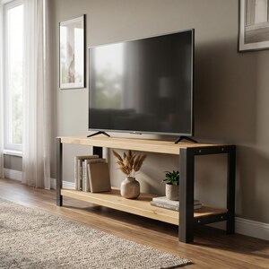 Op de afbeelding: Een moderne woonkamer met een tv-standaard van licht hout en zwarte metalen poten. Een grote flatscreen-tv staat op de standaard, met decoratieve items op de planken eronder. Een grijze bank, salontafel en vloerkleed maken de kamer compleet.