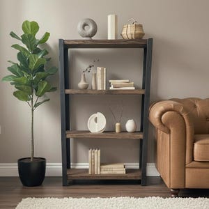 Op de afbeelding: Een hoge donkerhouten boekenkast met een zwart metalen frame, voorzien van vier planken gevuld met diverse decoratieve objecten en boeken. Daarnaast staat een grote groene vioolbladplant in een zwarte pot en een beige leren bank.