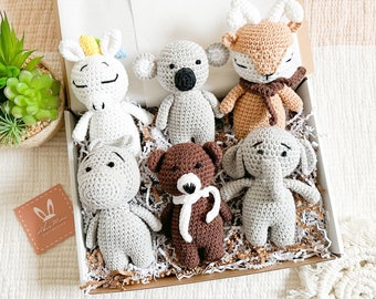 May include: A set of six crocheted stuffed animals in a gift box. The animals include a unicorn, koala, deer, hippopotamus, bear, and elephant. The animals are all gray except for the deer, which is brown.