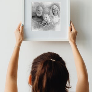 May include: A framed black and white pencil sketch of a family. The family consists of two adults and a child. The adults are standing behind the child, who is looking at the camera. The sketch is on a white background.