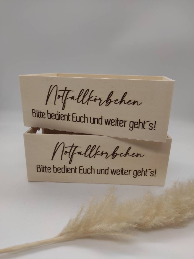 May include: Two wooden boxes with the text "Notfallk&ouml;rbchen Bitte bedient Euch und weiter geht's!"  engraved on the front.
