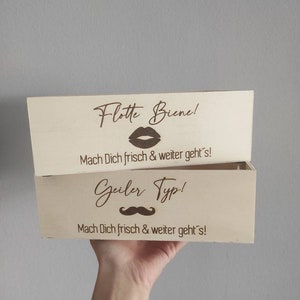 May include: Two wooden boxes with engraved messages. The top box says "Flotte Biene!" with a lipstick kiss graphic and "Mach Dich frisch & weiter geht's!" The bottom box says "Geiler Typ!" with a mustache graphic and "Mach Dich frisch & weiter geht's!"