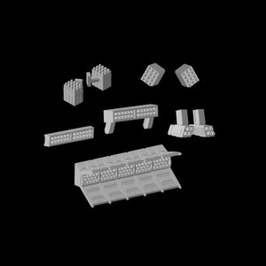 Puede incluir: Un conjunto de piezas de modelo de plástico gris para construir una nave espacial. Las piezas incluyen una variedad de formas y tamaños, incluida una pieza grande y plana con una serie de pequeños agujeros redondos.