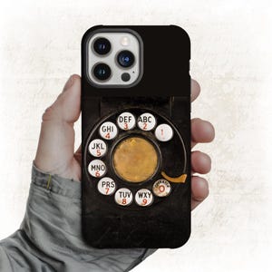 May include: A black phone case with a vintage rotary phone dial design. The dial has white numbers and letters, and the words "OPERATOR" and "GHI 4" are visible.