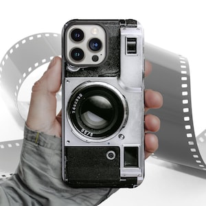 May include: A black and silver phone case with a vintage camera design. The case has a large lens and a silver body with black accents. The case has the numbers "7462090" and "2750" printed on it.