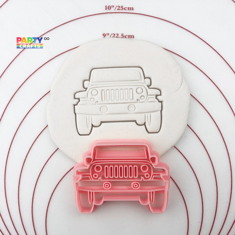 May include: Pink plastic cookie cutter shaped like a Jeep. The cutter is 9 inches or 22.5 centimeters wide.