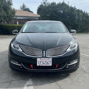 May include: Black sedan with a chrome grille and a California license plate. The car has a sleek design with a prominent front emblem. The license plate displays the number 1234567.