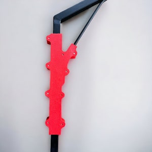 May include: A red and black metal wall-mounted crane with a red arm and black base.
