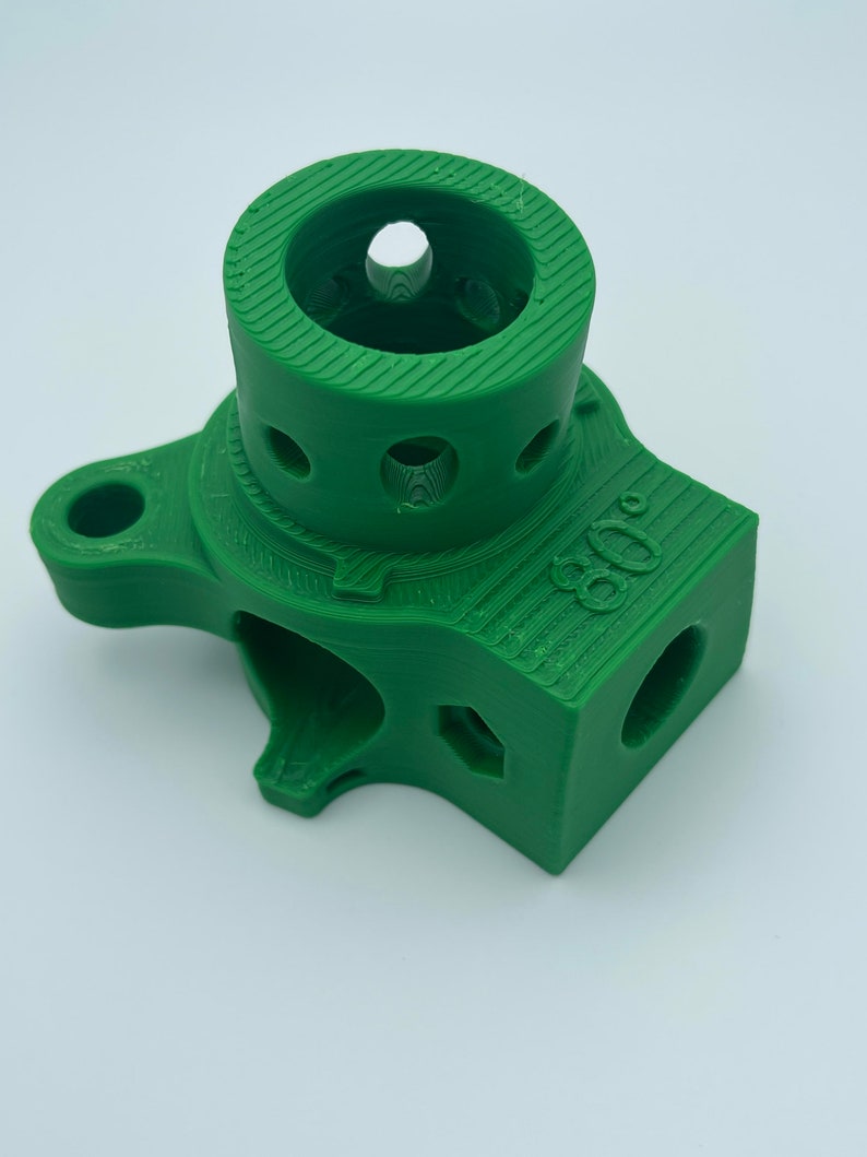 May include: Green 3D printed plastic part with a round opening and multiple holes. The part has the number "800" printed on it.
