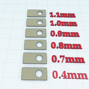 May include: A 3D rendering of six tan rectangular shapes, each with a circular hole. The shapes are arranged vertically, with red text indicating hole sizes from 0.4mm to 1.1mm. The background is a blue grid.