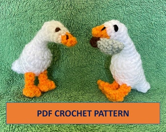 May include: Two white crocheted geese, one holding a gray crocheted object, on a green background. PDF CROCHET PATTERN is written in blue text on an orange banner.