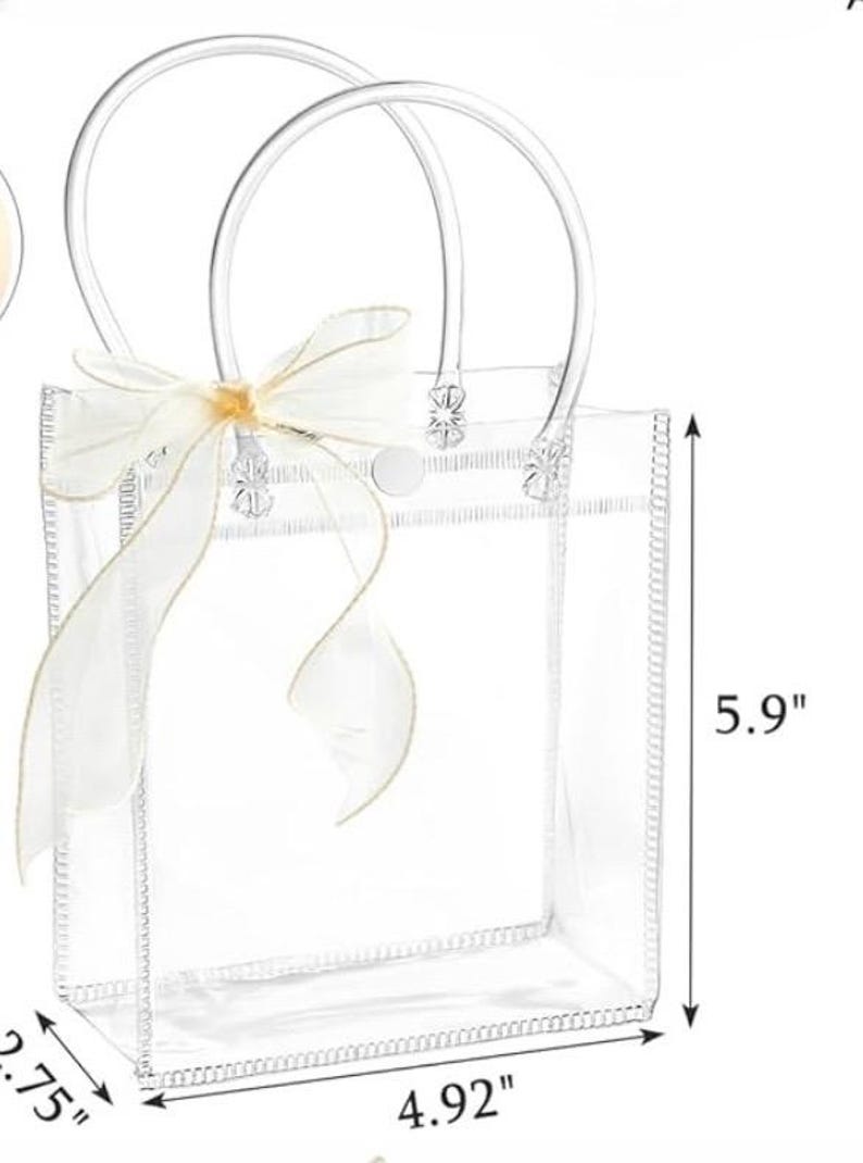 Puede incluir: Bolso tote transparente con un lazo de cinta blanco. El bolso tiene asas transparentes y mide 15 cm de alto, 12,5 cm de ancho y 7 cm de profundidad. El bolso est&aacute; hecho de un material transparente y tiene un lazo decorativo.
