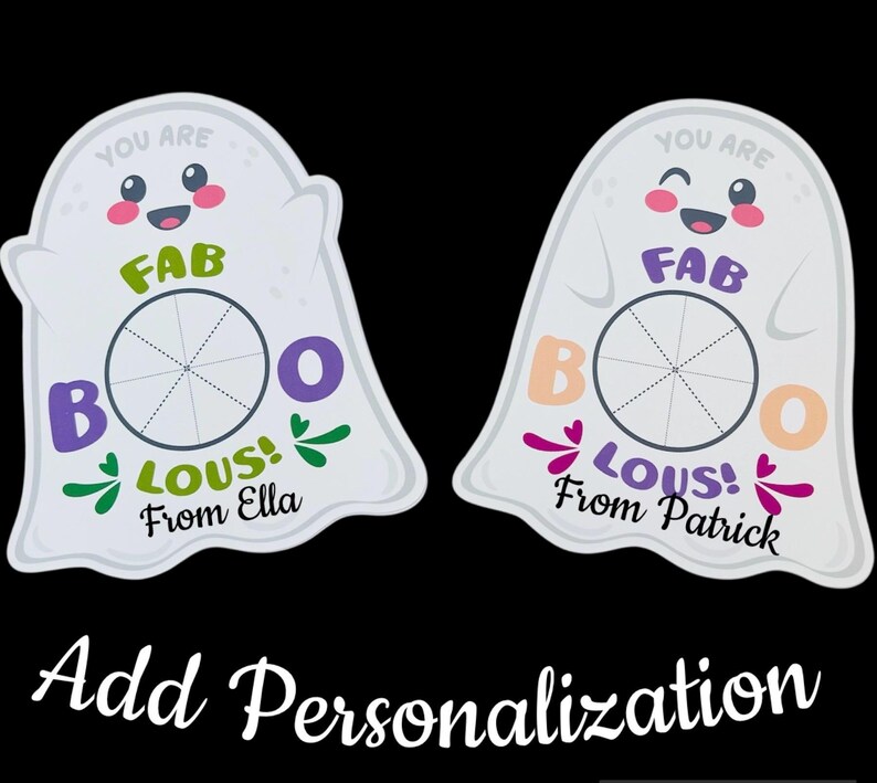 Op de afbeelding: Twee witte spookvormige decoraties met de woorden "YOU ARE FAB BOO LOUS!" en een naam. E&eacute;n heeft groene accenten en zegt "From Ella", de andere heeft paarse accenten en zegt "From Patrick". De zin "Add Personalization" staat onderaan.