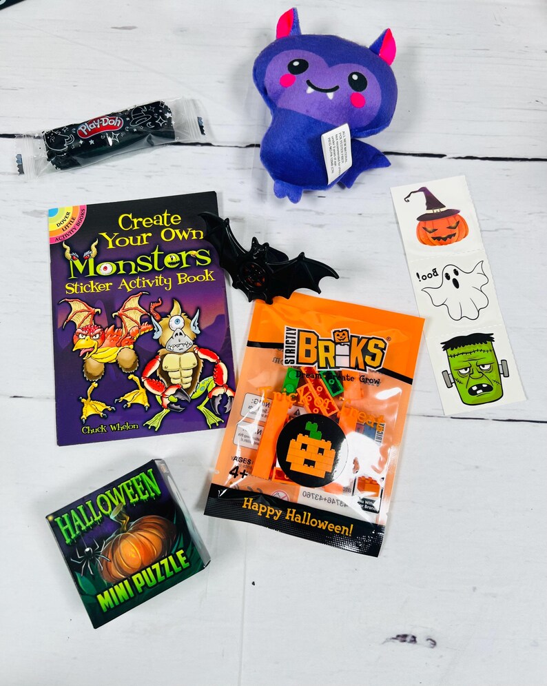 Puede incluir: Una colecci&oacute;n de art&iacute;culos con tem&aacute;tica de Halloween, que incluye un murci&eacute;lago de peluche, un libro de actividades con pegatinas, un mini rompecabezas, una bolsa de ladrillos de construcci&oacute;n y un recipiente de Play-Doh. El libro de pegatinas presenta ilustraciones de monstruos.