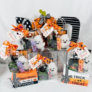 Puede incluir: Varias bolsas de regalo con tem&aacute;tica de Halloween llenas de golosinas y peque&ntilde;os juguetes. Cada bolsa incluye un fantasma de peluche, caramelos y una etiqueta que dice "You've Been Booed!". Las bolsas est&aacute;n decoradas con cintas naranjas y negras.