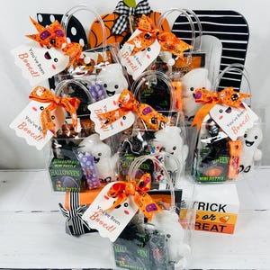 Puede incluir: Bolsas de regalo tem&aacute;ticas de Halloween llenas de golosinas y juguetes. Cada bolsa transparente contiene un peluche de fantasma blanco, caramelos y un mini rompecabezas. Las bolsas est&aacute;n adornadas con lazos naranjas y negros y la etiqueta "You've Been Booed!"