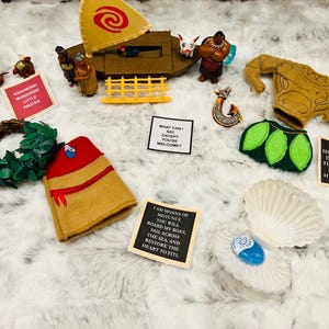 May include: A collection of felt crafts inspired by the Disney movie Moana. The set includes a felt boat, a felt Maui, a felt Moana, a felt seashell, and a felt lei. The felt crafts are all handmade and feature intricate details.