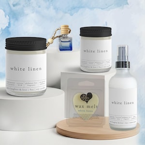 May include: A collection of home fragrance products, including candles, wax melts, and room spray. The products feature the text "white linen" on the labels. The candles are in glass jars with black lids. The wax melts are heart-shaped.